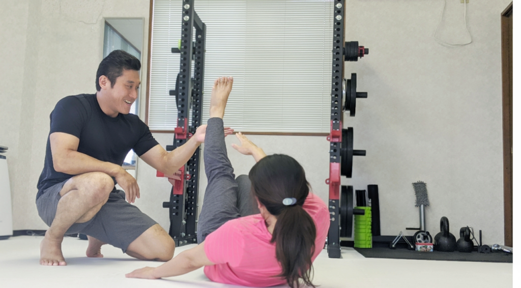 トレーナーがマンツーマンでストレッチを手伝っている様子